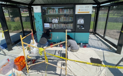 Two artists painting a mural on the Cochran Kiosk