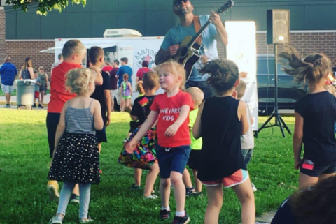 Man playing guitar and kids dancing.