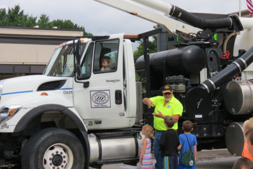 City worker showing children a truck.