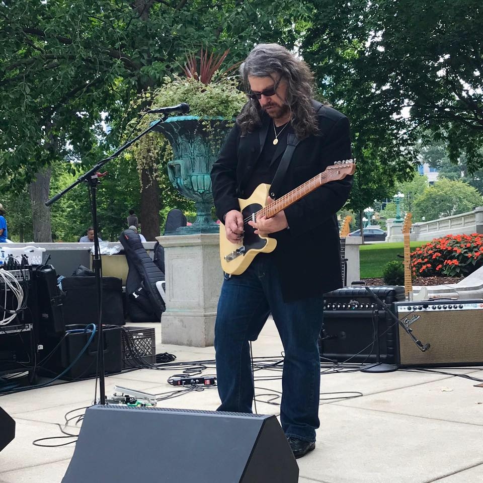 Joey Leone playing guitar in a park