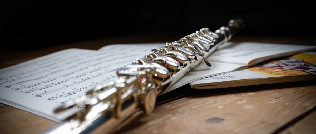 A flute laying across a book of music