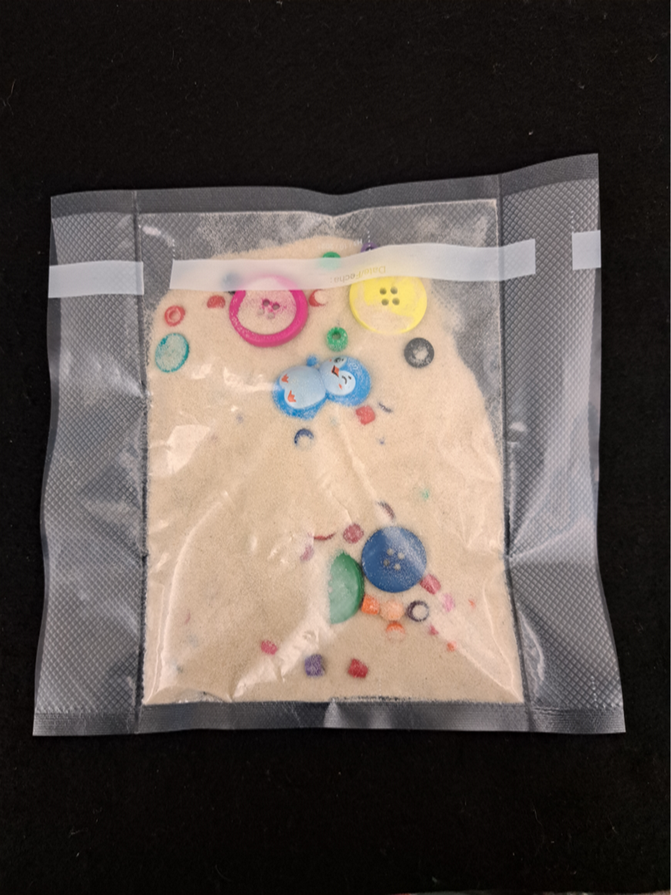 Bag with sand, buttons and small toys in it.