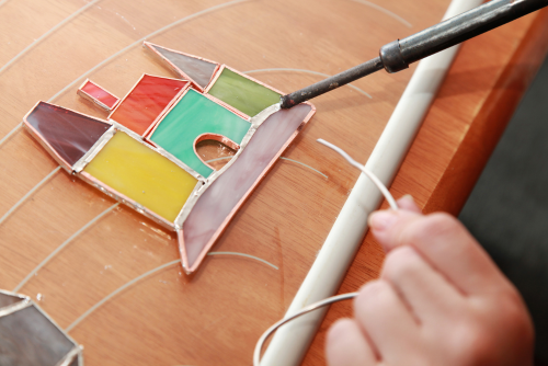 Unidentified hands soldering a stained glass castle